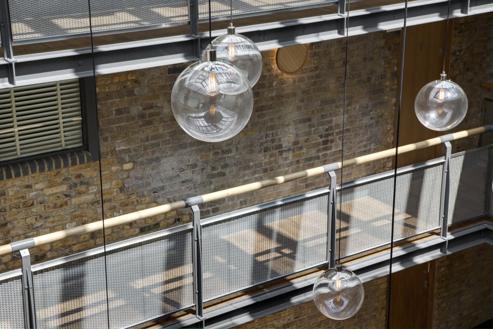 Residential apartment building atrium - Wapping High Street | Close-up of chandelier pendants, restored timber rail and steel mesh frames | Interior Designers